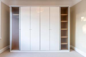 a closet with white cabinets in a room at A Piece of Seaside Serenity on the Sandbanks Peninsula in Sandbanks