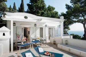 Casa blanca con patio con mesa y sillas en Villa Bouganvillea Superb Capri Villa with Views en Capri