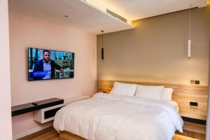 1 dormitorio con 1 cama y TV en la pared en Lakehouse Apartment - Lake Powell - One Bedroom Apartment with Balcony, en Abuja
