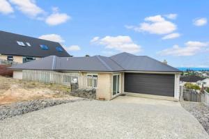 a large house with a garage on a hill at Opal of Orewa with pool, spa and ocean views in Orewa