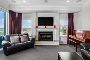 a living room with a fireplace and a television at Opal of Orewa with pool, spa and ocean views in Orewa