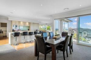 a kitchen and dining room with a table and chairs at Opal of Orewa with pool, spa and ocean views in Orewa