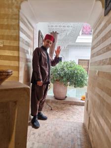 Un uomo in piedi in un corridoio in una casa di Riad Les Nuits de Marrakech a Marrakech