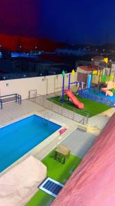 una piscina con scivolo e un parco giochi di شاليهات ميرامار مكة الحسينية a Ash Shishah