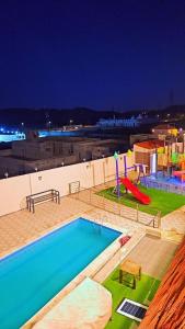 una piscina con scivolo e un parco giochi di شاليهات ميرامار مكة الحسينية a Ash Shishah