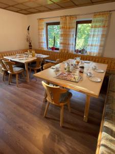 ein Esszimmer mit Tischen, Stühlen und Fenstern in der Unterkunft Gästehaus Grünberger in Hutthurm