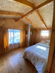 ein Schlafzimmer mit einem Bett in einem Holzhaus in der Unterkunft Cabañas León in Ancud