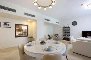uma sala de estar com uma mesa branca e cadeiras em Livbnb Suites - Stylish 2BR -City & Burj Khalifa View em Dubai