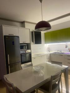een keuken met een witte tafel en een zwarte koelkast bij Emma & Ella Apartment in Tirana