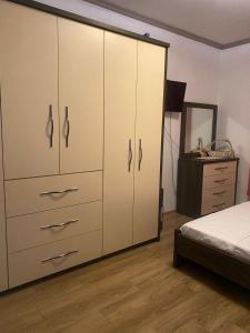 a bedroom with white cabinets and a bed and a dresser at Emma & Ella Apartment in Tirana