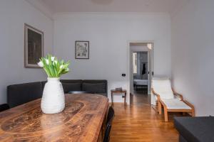 una sala de estar con un jarrón de flores sobre una mesa de madera en Belle Arti Zen Apartment, en Roma