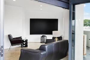 a living room with a black leather couch and a flat screen tv at Freeman Escape with garage parking in Auckland
