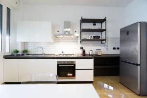 a kitchen with white cabinets and a stainless steel refrigerator at Realkasa Kharkov Apartment in Bologna