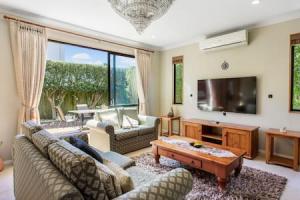 a living room with a couch and a tv at Northpark Getaway with patio area in Auckland