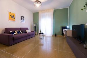 a living room with a purple couch and a television at Realkasa Kharkov Apartment in Bologna
