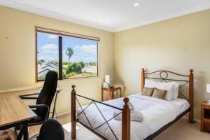 a bedroom with a bed and a desk and a window at Northpark Getaway with patio area in Auckland