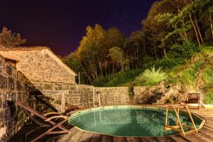 een klein zwembad met een houten terras en een nachtelijke hemel bij Il Mulino in Ortignano Raggiolo
