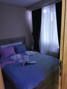 a bedroom with a bed with purple sheets and a window at APARTMAN 94 in Zlatibor +3 photos