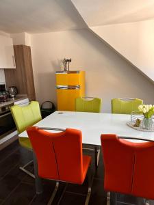 kuchnia z białym stołem i kolorowymi krzesłami w obiekcie Schönes Zimmer im Zentrum - 2 w mieście Paderborn