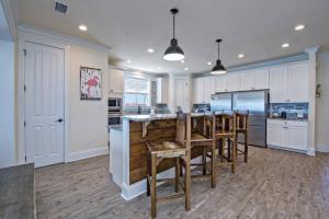 een keuken met witte kasten en een bar met krukken bij BeachFront 5Bed EasyBreezy West in Gulf Shores