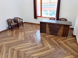 a room with a table and chairs and a wooden floor at RajDarbar 