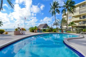 a swimming pool in front of a building with palm trees at Palms 407 in Islamorada