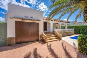 a house with a wooden door and a palm tree at Aure Villa con piscina y aire acondicionado! in Cala'n Bosch