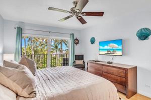 a bedroom with a bed with a ceiling fan and a desk at Palms 417 in Islamorada