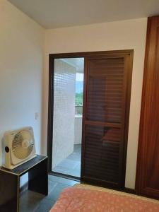 a room with a bedroom with a fan and a window at Apartamento Riviera Velas in Bertioga