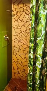 a shower curtain in a bathroom with a stone wall at Moonsong Accommodation & Camping in Plettenberg Bay