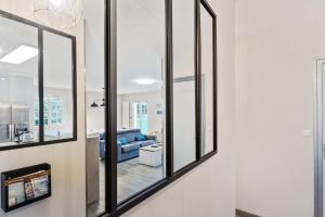 ein Wohnzimmer mit 3 Fenstern und einem blauen Sofa in der Unterkunft Maison Marouette - Welkeys in Aytré