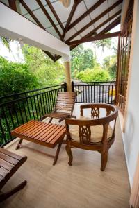 a porch with two benches and a table on a balcony at Manel Villa in Ahangama