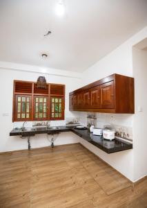 a kitchen with white walls and wooden cabinets at Manel Villa in Ahangama