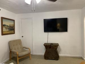 sala de estar con silla y TV en la pared en Beach Side Studio #2 apts, en North Camellia Acres