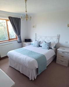 a bedroom with a large white bed and a window at Woodpeckers Cottage B&B in Pett