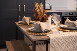 a table with plates and wine glasses on it at Modern, Stylish, cosy, Finchley London 3 Bed 2 bath Apartment with Free Parking in Whetstone