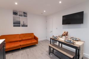 a living room with an orange couch and a table at Modern, Stylish, cosy, Finchley London 3 Bed 2 bath Apartment with Free Parking in Whetstone
