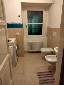 a bathroom with a toilet and a sink and a window at La stufa rossa in Sondrio