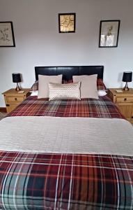 a bedroom with a large bed with a plaid blanket at Woodpeckers Cottage B&B in Pett