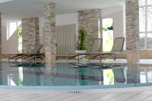 una piscina con 2 sillas y una piscina en Schwarzwaldhotel Gengenbach, en Gengenbach