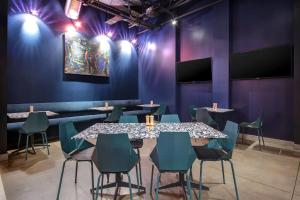 uma sala de jantar com paredes roxas, mesas e cadeiras em Aloft Oklahoma City Downtown – Bricktown em Oklahoma City
