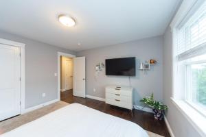 um quarto com uma cama branca e uma televisão de ecrã plano em Ultra-Luxurious Home near Boston (Pet-Friendly) em Waltham