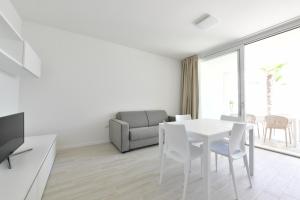 een witte woonkamer met een witte tafel en stoelen bij Wave Plus Apartments in Lido di Jesolo