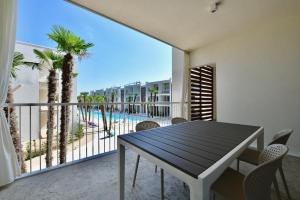 een eetkamer met een tafel en een balkon met een zwembad bij Wave Plus Apartments in Lido di Jesolo