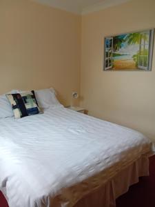 ein Schlafzimmer mit einem weißen Bett mit einem Bild an der Wand in der Unterkunft Ensuite Double Room in London