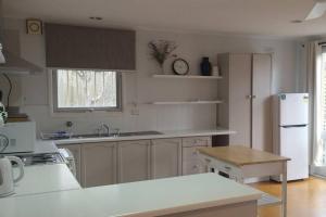 a kitchen with white cabinets and a white refrigerator at Happy Spacious Home nr Canberra Hospital in Harman