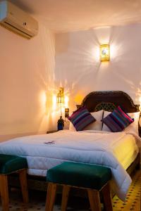 a bedroom with a large bed with two green seats at Riaad Hamad in Fez