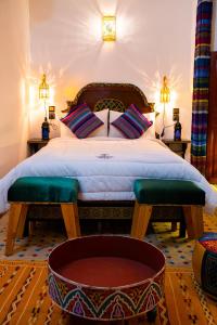 a bedroom with a large bed with two benches and a tub at Riaad Hamad in Fès