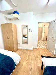 biały pokój z 2 łóżkami i drewnianą podłogą w obiekcie Brilliant One Bedroom Flat in London w Londynie