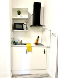 a white kitchen with a sink and a microwave at Brilliant One Bedroom Flat in London in London